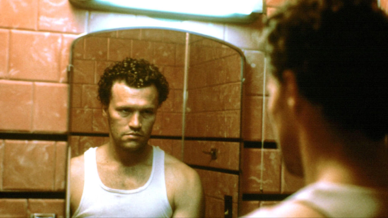 img_4346 | Filmmaker Magazine A man in a white undershirt stares into a grimy mirror.