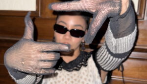 A woman performs the "framing a shot" hand pose.